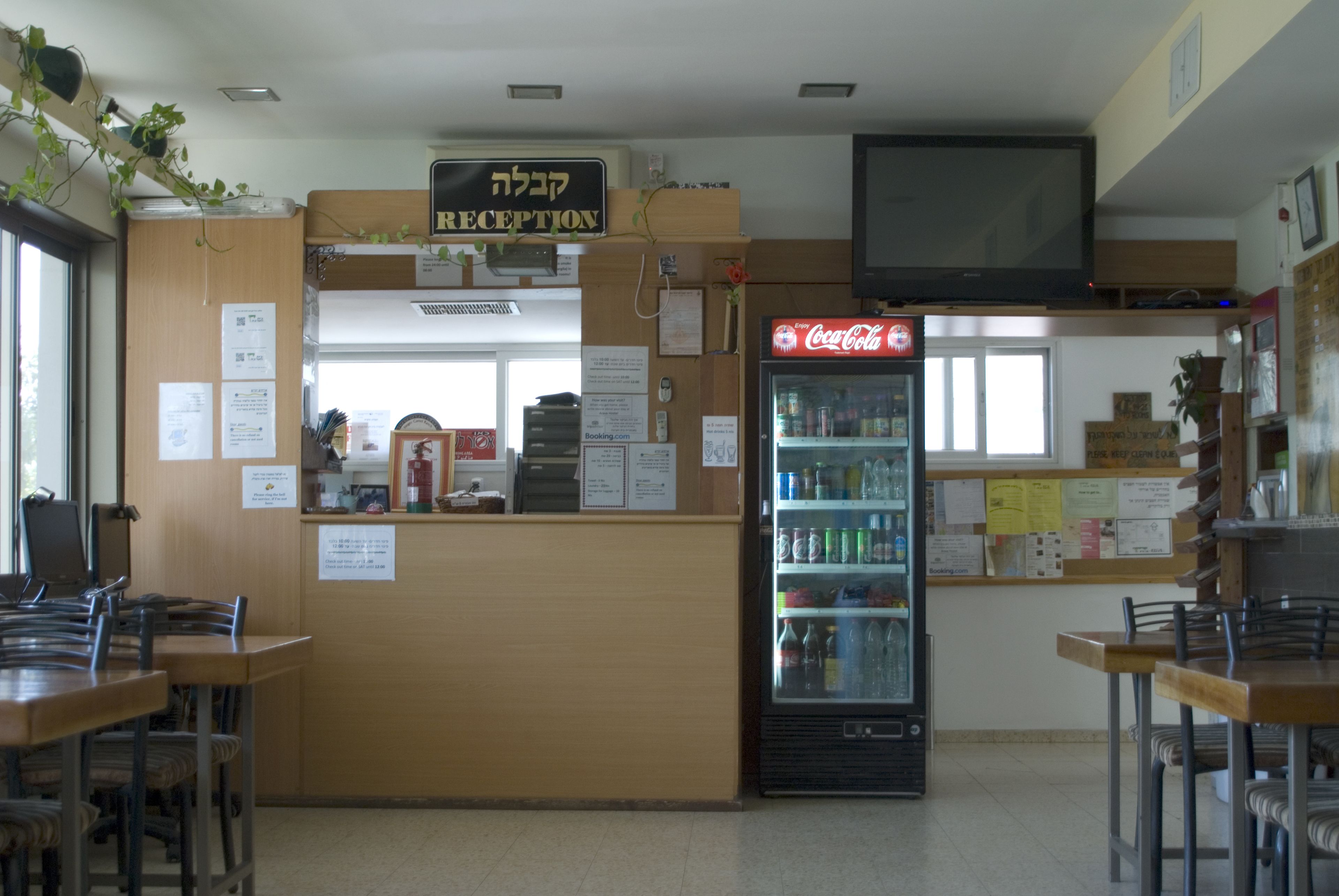 A reception area with a Coca-Cola refrigerator, wooden reception desk, and a television mounted on the wall.