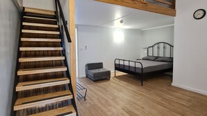 A spacious room with a wooden staircase, a loft area, and a bed. - Arava Hostel (Eilat)