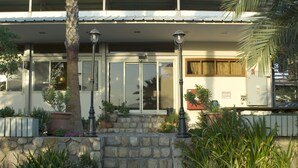 A building with a stone entrance, potted plants, and a metal railing. - Arava Hostel (Eilat)