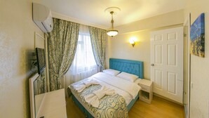 A neatly arranged bedroom with a bed, bedside table, and a mirror. - Ancient Town Hotel (Istanbul)