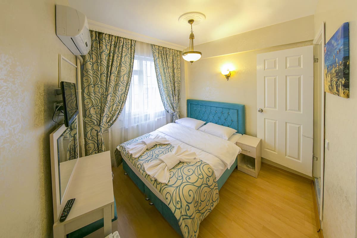 A neatly arranged bedroom with a bed, bedside table, and a mirror.