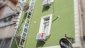 A building with a green facade, multiple air conditioning units, and a sign indicating it is a hotel named "Ancient Town." - Ancient Town Hotel (Istanbul)