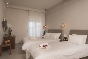 A hotel room with two beds, a desk, and a nightstand. - Filoxenia (Volos)