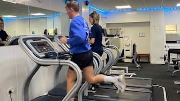Uma academia com esteiras, espelhos e aparelhos de ginástica.