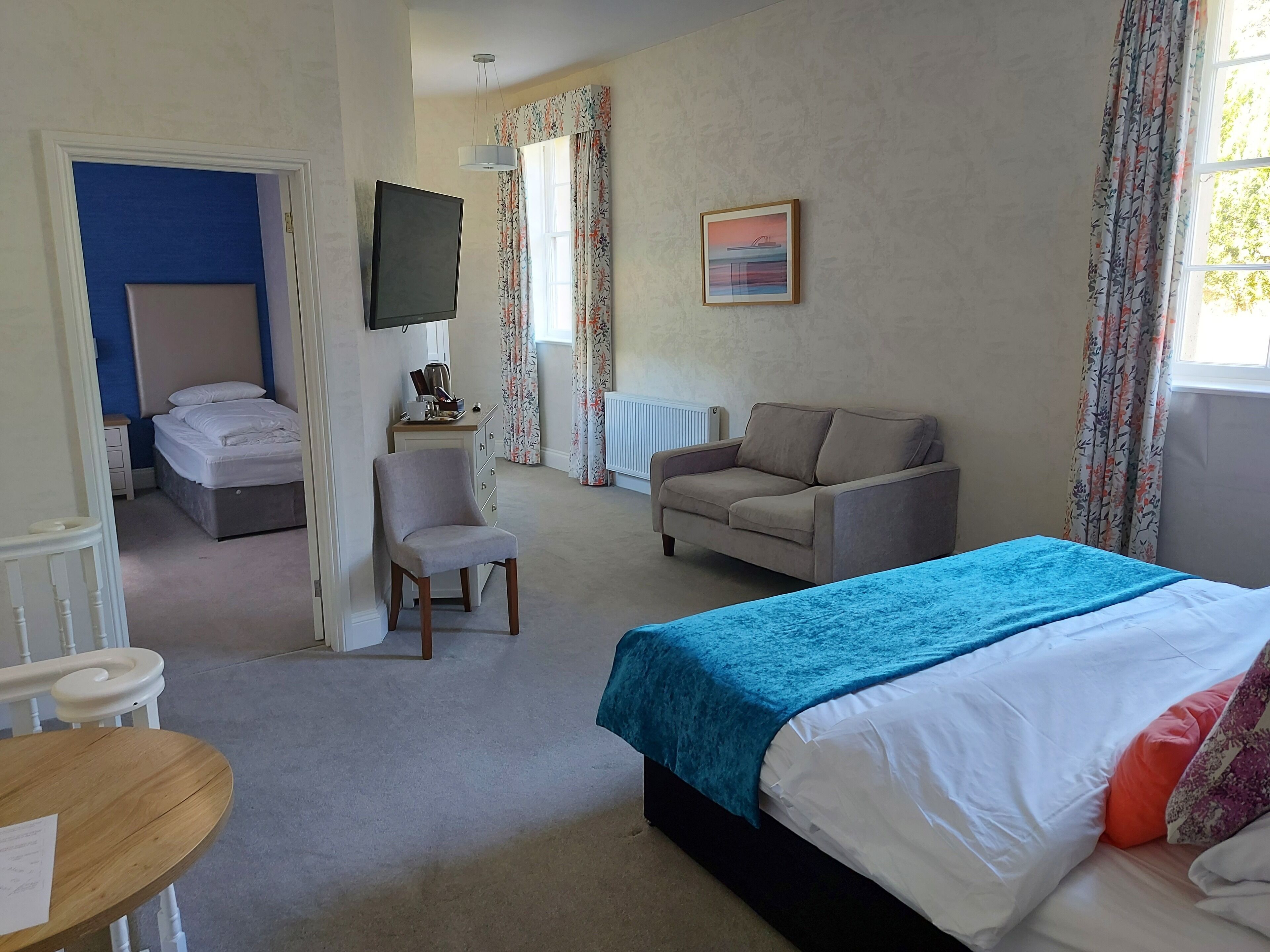 A hotel room with a bed, a desk, a chair, a sofa, and a TV.