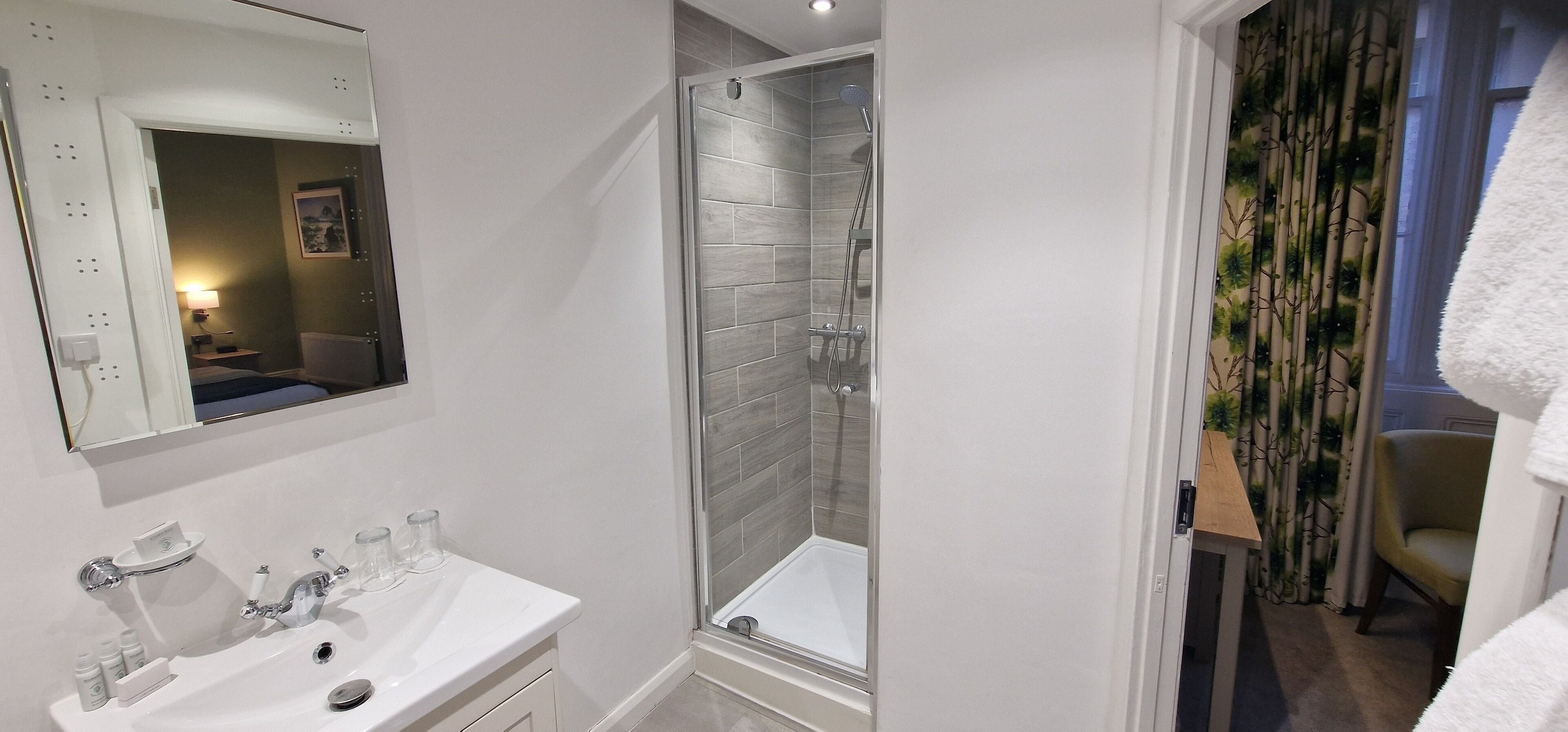 A bathroom with a white sink, mirror, and shower.
