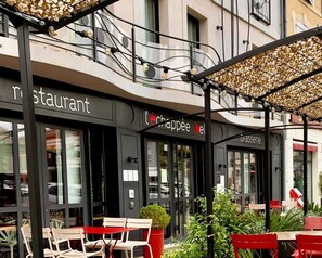 Un café al aire libre con mesas y sillas, un letrero que dice 'Le Chappelle' y un letrero de 'brasserie'.