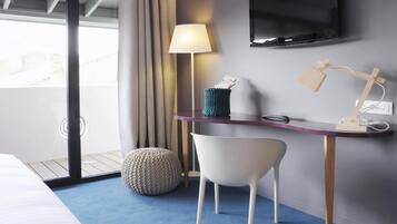 Una habitación de hotel moderna con cama, escritorio con lámpara, televisión y vistas al exterior.