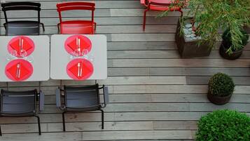 An outdoor dining area with tables and chairs arranged on a wooden deck.