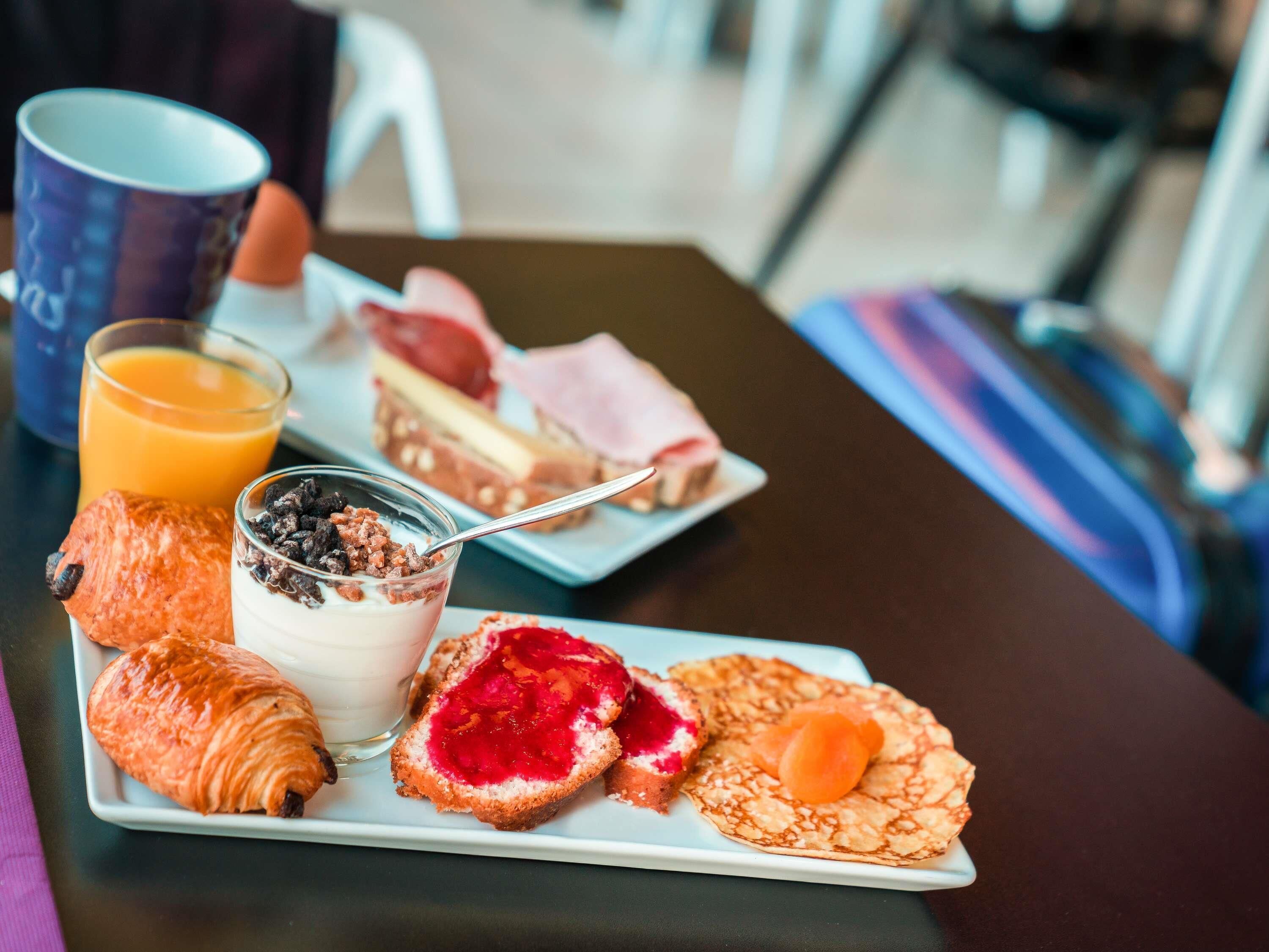 A breakfast plate with croissants, a glass of orange juice, a dessert, and a pastry.