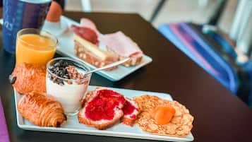 A breakfast plate with croissants, a glass of orange juice, a dessert, and a pastry.