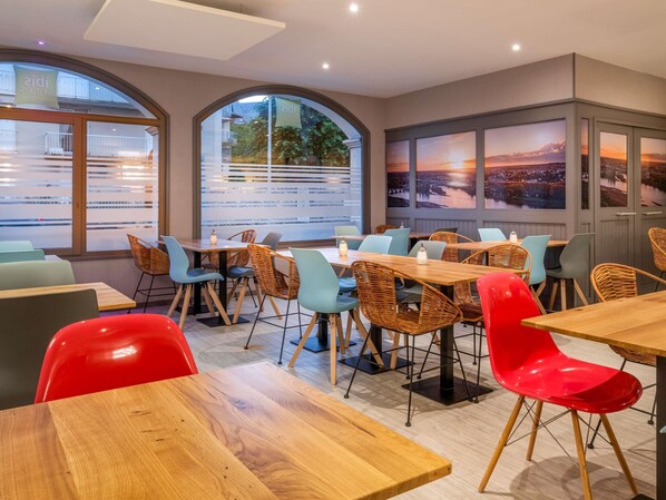 A dining area with tables and chairs, large windows with views, and a modern interior design.