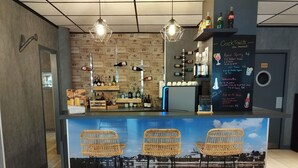 A bar area with wicker chairs, a counter with bottles, and a chalkboard menu. - ibis Styles Blois Centre Gare (Blois)