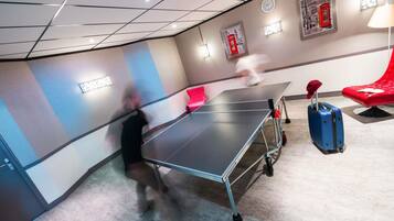 Una mesa de ping pong en una habitación con un reloj y una imagen de una cabina telefónica roja en la pared.