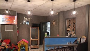 A hotel reception area with a wooden desk, a large window displaying a cityscape, and a wall-mounted clock. - ibis Styles Blois Centre Gare (Blois)