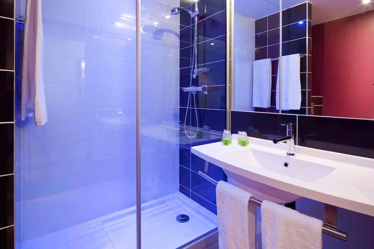 Une salle de bain moderne avec une douche à parois de verre, un lavabo blanc et un miroir.