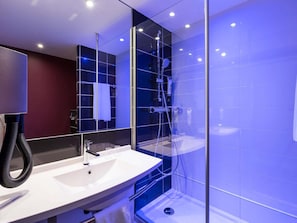 Une salle de bain moderne avec une douche à parois de verre, un lavabo blanc et un miroir.