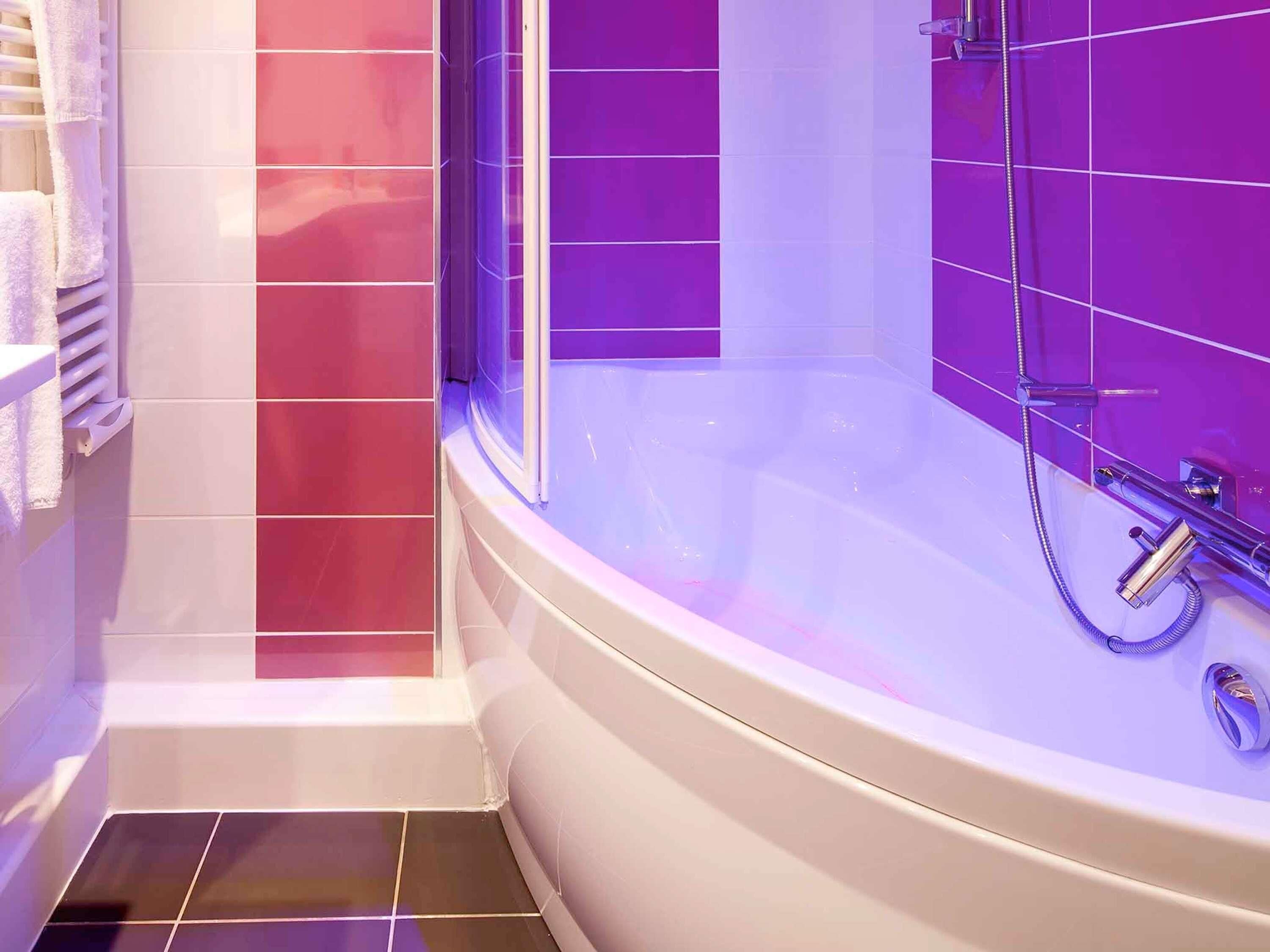 A bathroom with a bathtub, a shower, and tiled walls.