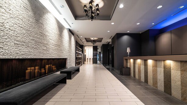 A modern lobby with a long bench, a reception desk, and a chandelier. - Hotel Vista Sapporo Odori (Sapporo)