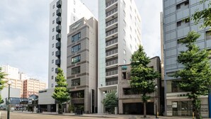 A modern multi-story building with a mix of residential and commercial spaces, featuring balconies, large windows, and a parking garage. - Hotel Vista Sapporo Odori (Sapporo)