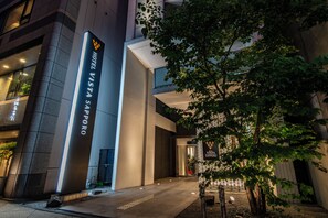 A modern hotel entrance with a prominent sign, a covered walkway, and a landscaped area with trees. - Hotel Vista Sapporo Odori (Sapporo)
