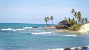 A beach with palm trees, a hut, and a rocky shoreline. - Moriah Natal Beach Hotel (Natal)