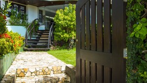 A stone pathway leading to a gated entrance with a staircase and a modern building in the background. - Divi Divi Praia Hotel (Natal)