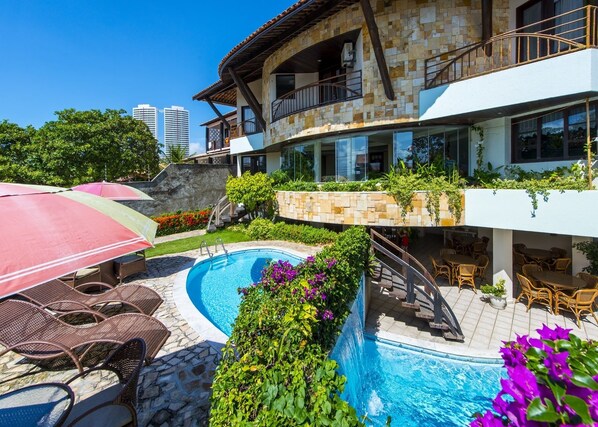 A modern villa with a swimming pool, outdoor seating, and lush landscaping.