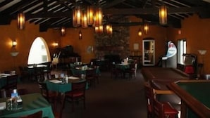 Un restaurante con varias mesas y sillas, una pared de piedra y lámparas colgantes.