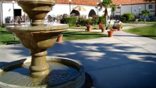 Una fuente en un patio con techo de tejas y plantas en macetas.
