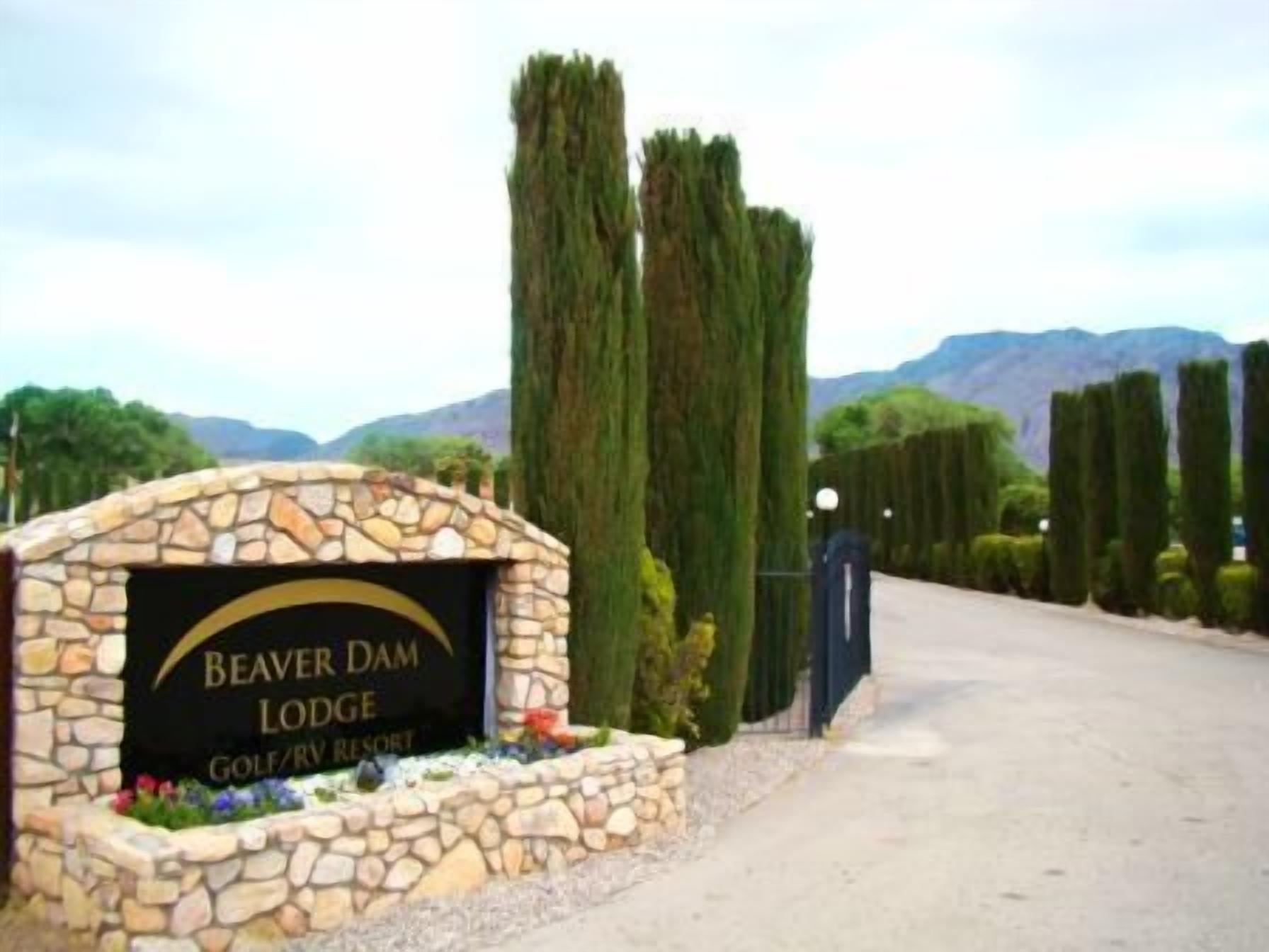 Un letrero de piedra con la inscripción "Beaver Dam Lodge Golf/RV Resort" rodeado por un muro de piedra y plantas decorativas.