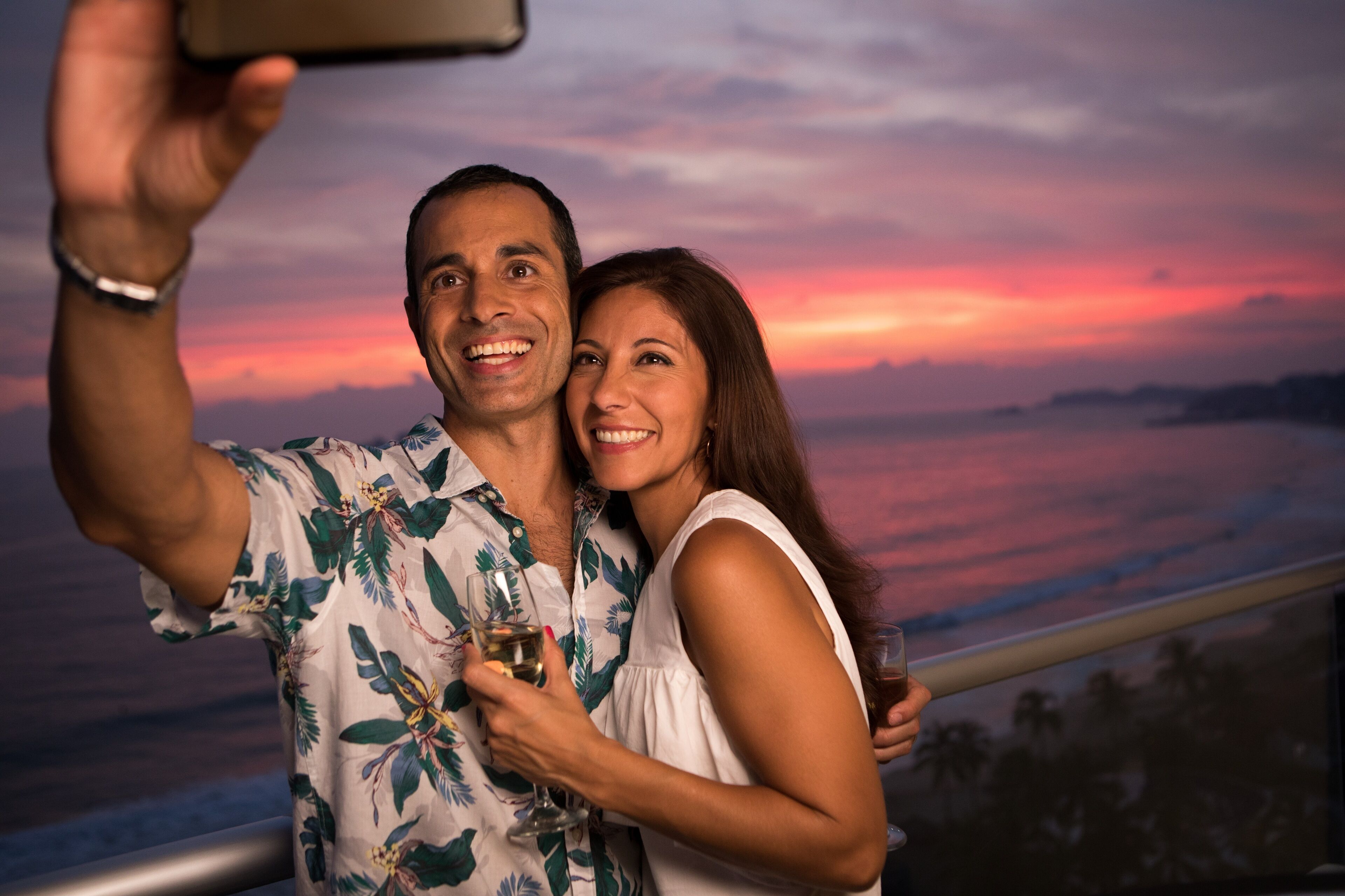 A couple taking a selfie with a scenic sunset view in the background.