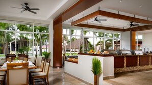 A spacious dining area with a high ceiling, large windows, and a central island with a grill.