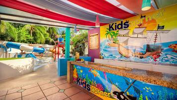 A children's play area with a colorful mural, slides, and a beach-themed play structure.
