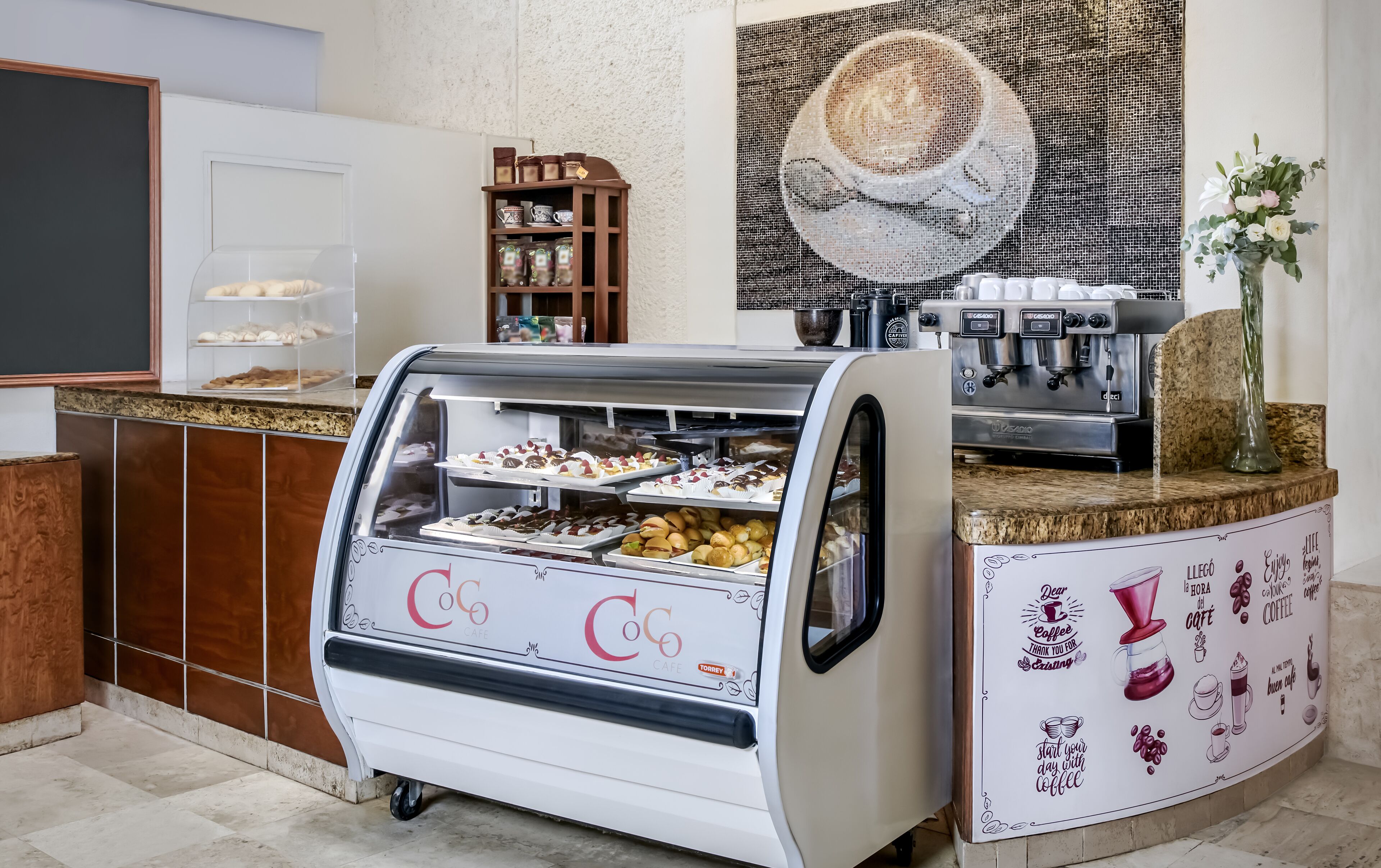 Um café com uma vitrine de doces e uma máquina de café.