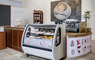Um café com uma vitrine de doces e uma máquina de café.