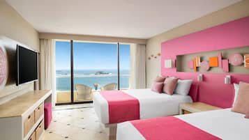 A hotel room with two beds, a TV, a balcony with a view of the sea, and decorative wall art.