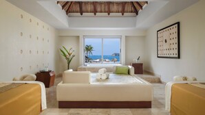 A spacious room with a large bed, a sofa, and a view of the beach.