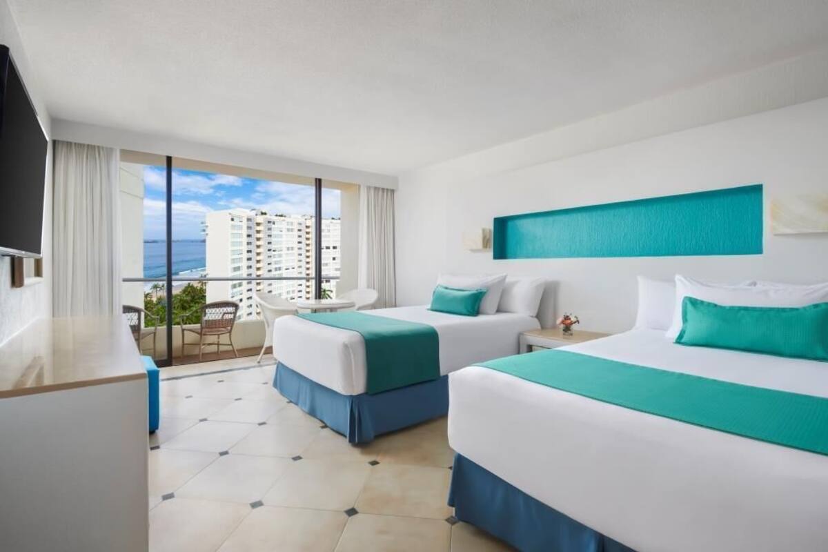 A hotel room with two beds, a balcony, a TV, and a view of the city.