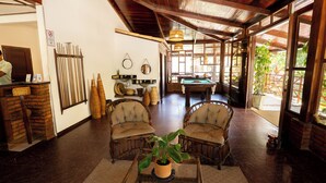 A spacious room with a pool table, wicker chairs, and a potted plant. - Pousada Bicho Preguiça Pipa - RN (Tibau do Sul)