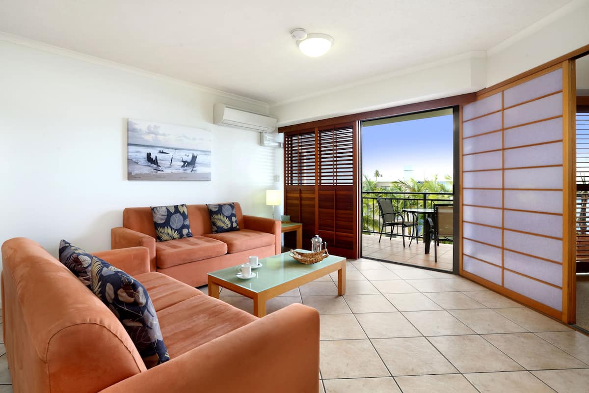 A living room with a sofa, a coffee table, and a view of a balcony with a sliding door.