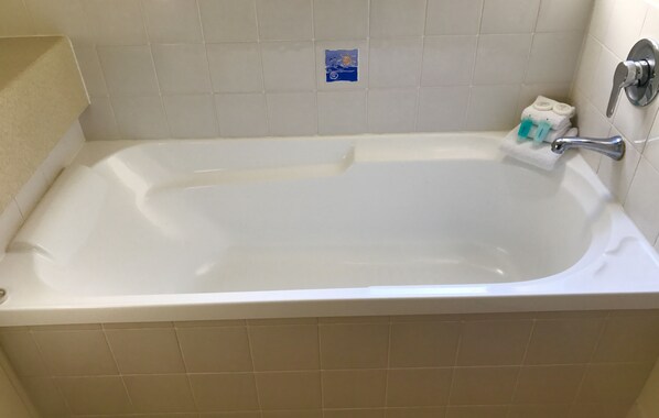 A standard bathtub with a faucet and a small towel rack with a few towels.