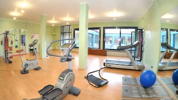 A gym with treadmills, elliptical machines, and exercise balls.