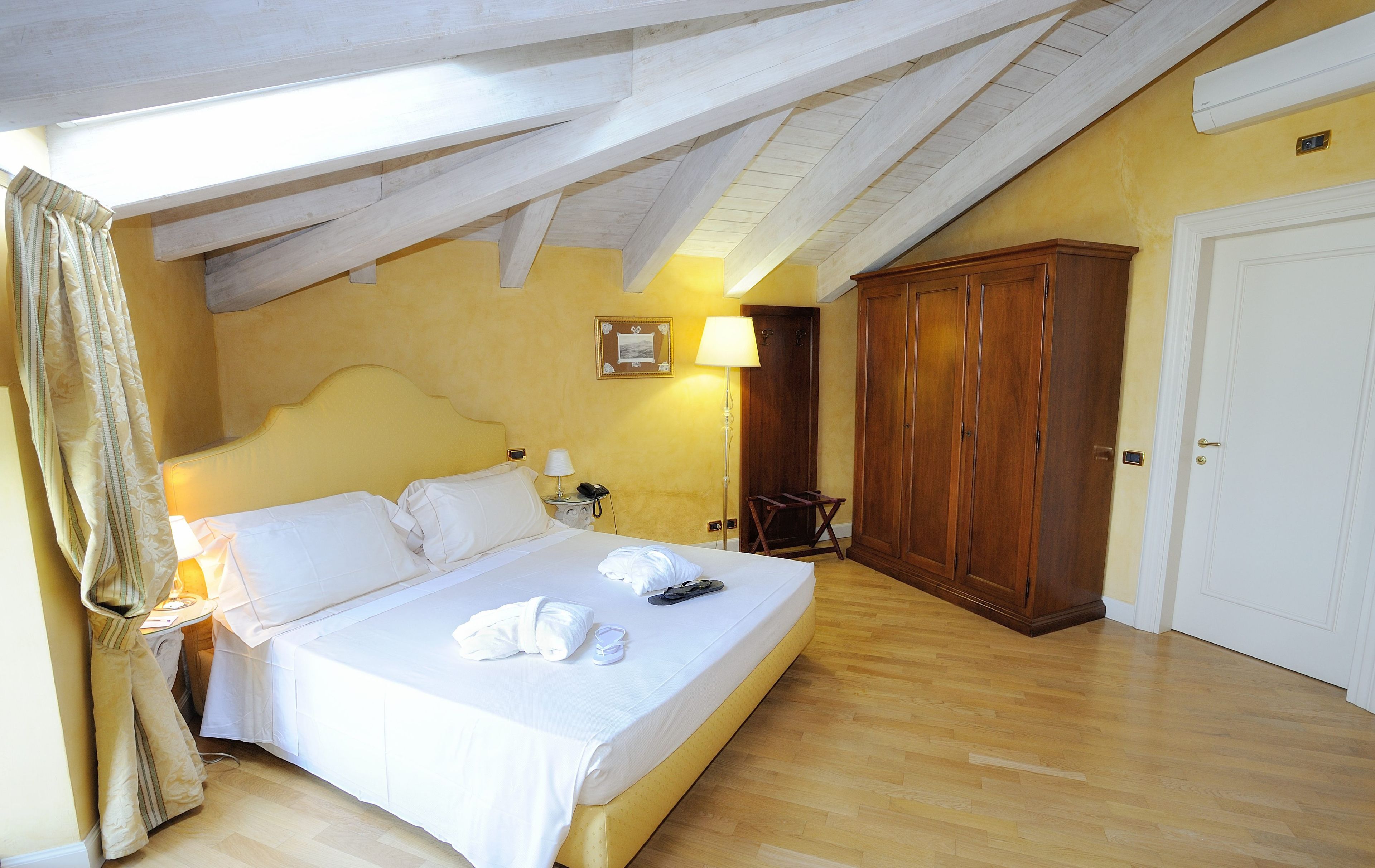 A hotel room with a bed, wooden wardrobe, and a door.