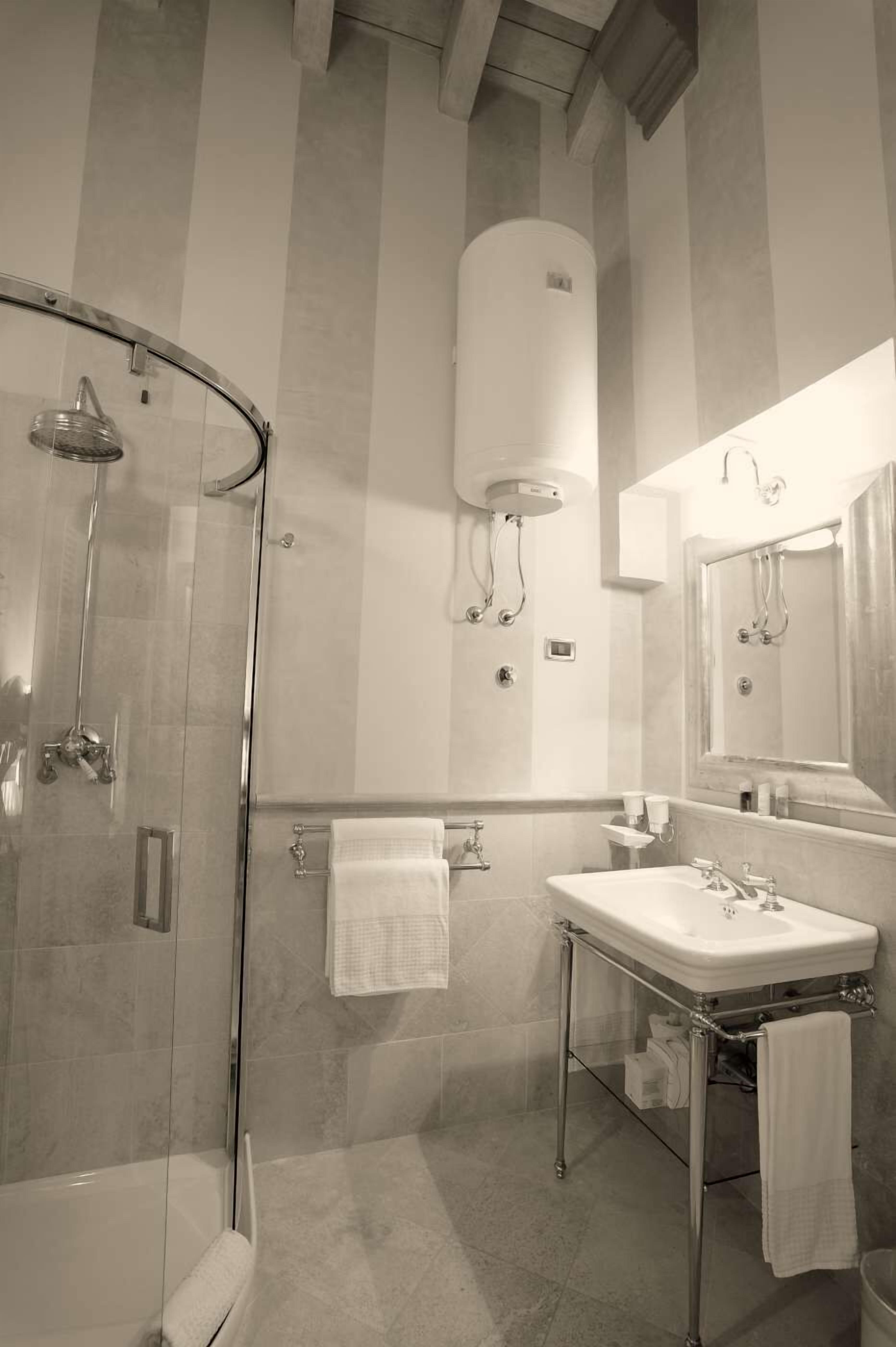A modern bathroom with a glass-enclosed shower, a large mirror, and a white sink.