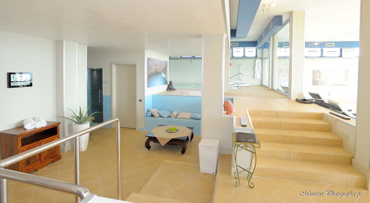 Un'ampia zona giorno con una scala che conduce a un balcone, un tavolino con una ciotola e un televisore montato a parete.