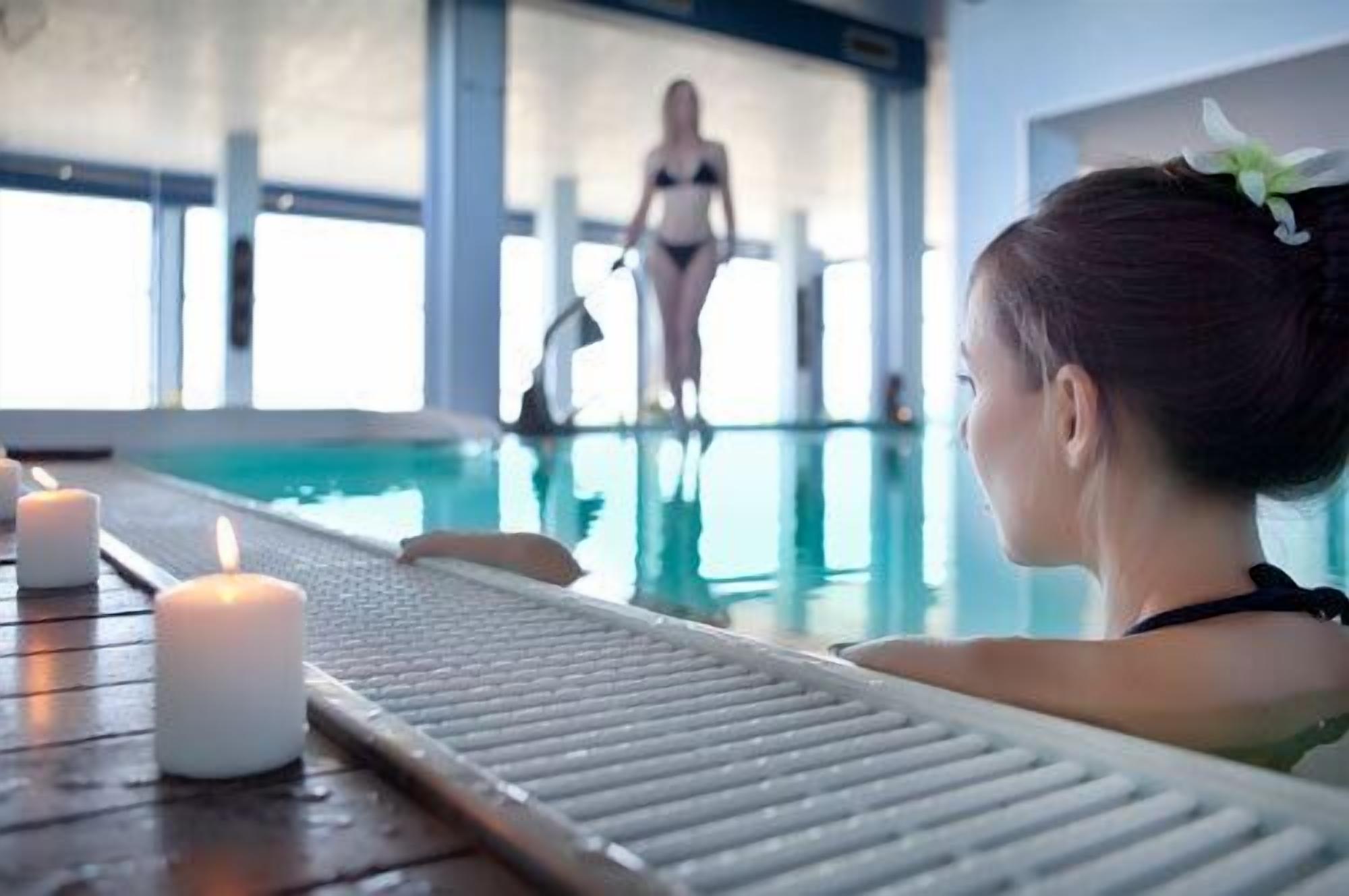 Una piscina interior con una persona caminando al fondo.