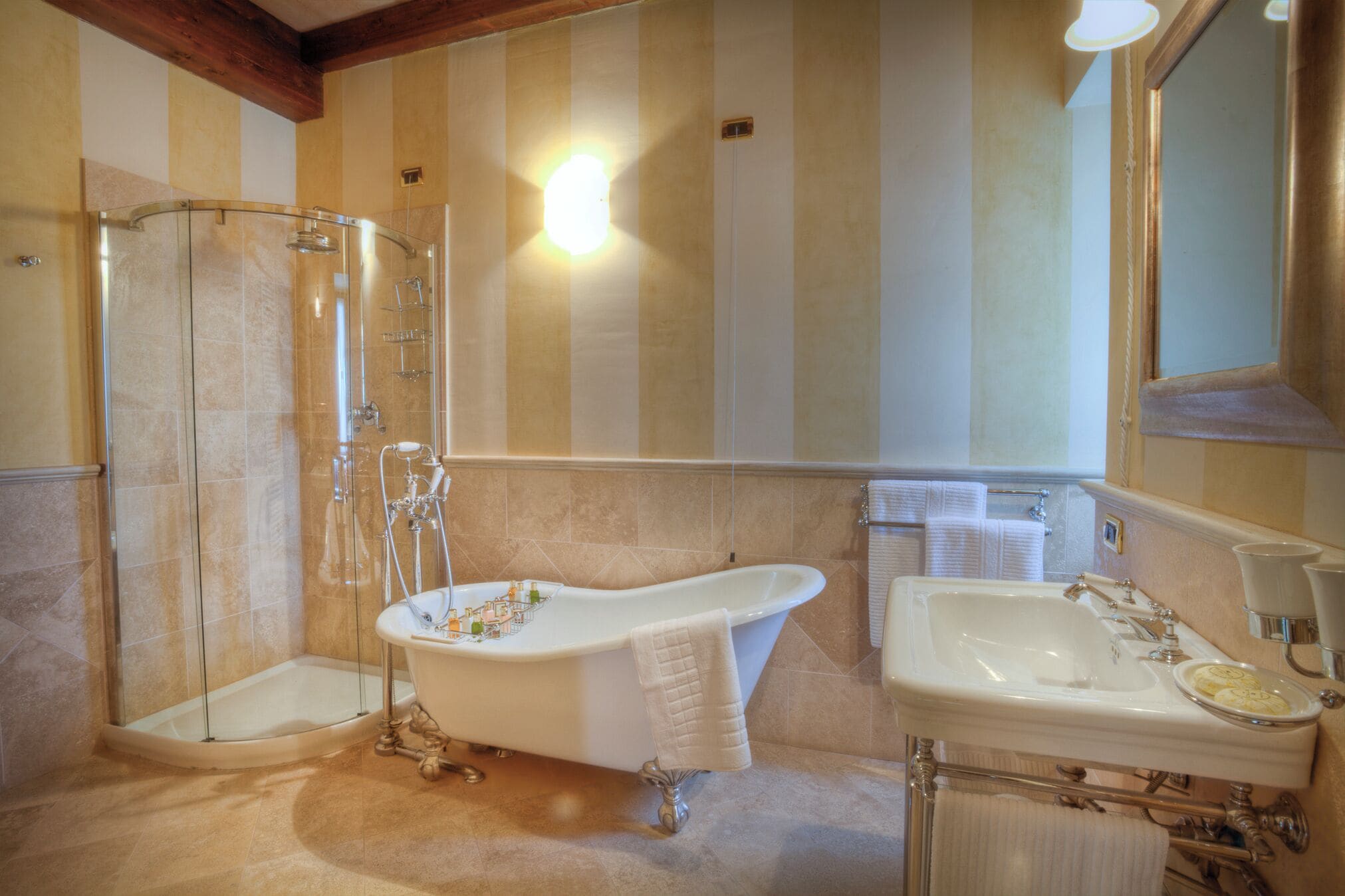 A bathroom with a glass-enclosed shower, a freestanding bathtub, and a vanity with a sink and mirror.