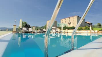 Relax by the serene pool surrounded by lounge chairs and umbrellas.