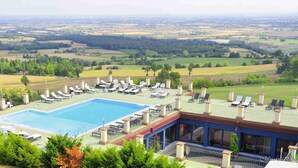 Un espace piscine doté de chaises longues et offrant une vue sur la campagne.